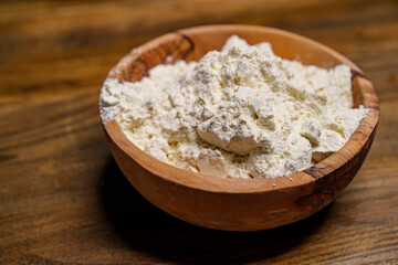 flour in a wooden dish on the kitchen table. 