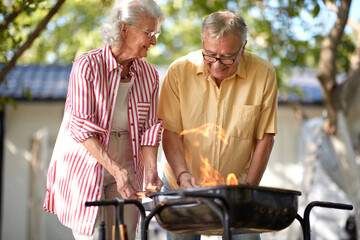 elderly couple making fire for barbeque