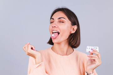 Woman in sweater on gray background with pills taking pill happy cheerful positive health concept