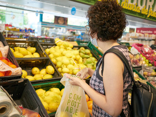 A woman wears a face mask while shopping in a supermarket
