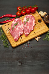 Fresh raw beef or pork steaks on wooden cutting board
