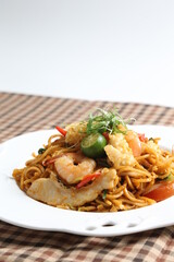 stir fried spicy chilli noodle mamak mee goreng with mixed seafood fish, prawn, squid, meat and lime asian halal menu