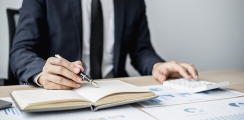 Businessman takes notes on a topic that examines information from finance documents to bring to department and partnership meetings, preparing monthly meeting information. Financial management concept