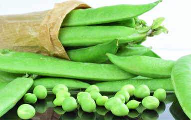 Close up, scattered peas, behind more in whole pieces, split in a kraft paper bag.