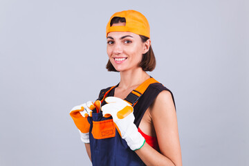 Painter worker woman in overalls and gloves on gray background with calm confident smile look to camera
