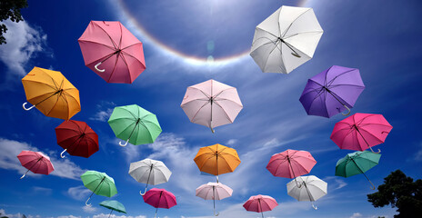 Colorful umbrellas are suspending in the air with sun halo and clear blue sky cloud in background