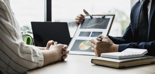 Two businessmen are meeting together on the topic of monthly finance, financial documents prepared by the finance department. Concept of financial management according to company policy.