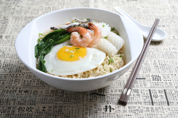 chef cook noodle mee soup with mixed seafood prawn, squid , fish, fried egg and vegetable asian halal menu