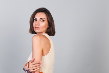 Beautiful woman in top and plaid shirt on gray background with makeup  positive confident smile, happy emotions