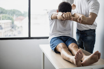 A professional physiotherapist is stretching the back muscles for patients who undergo therapy,...