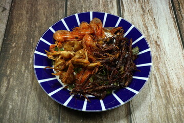 Traditional famous snack in Thailand. Pile of deep fried insect (bugs), little shrimp and crab serving on the plate.