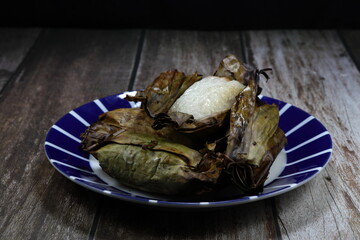 Pile of traditional Thai coconut sticky rice in banana leaf serving on the plate. Famous ancient sweet snack in Asia. 