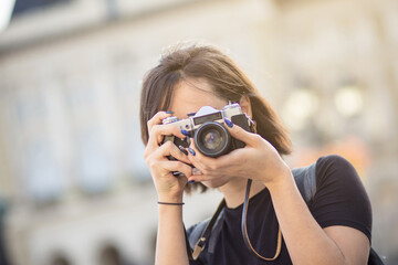  Young woman taking photo in the city with camera.