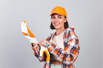 Beautiful woman in plaid shirt, hat wearing gloves, house worker ready to repair house