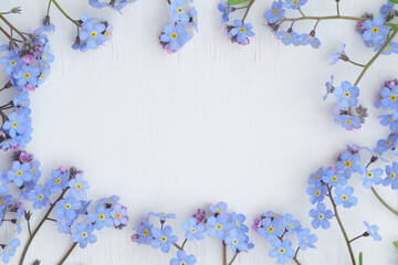 Fototapeta na wymiar Frame of spring flowers forget-me-nots on a white wooden background close-up