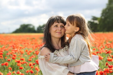 Mother and daughter are walking in a beautiful field of poppies