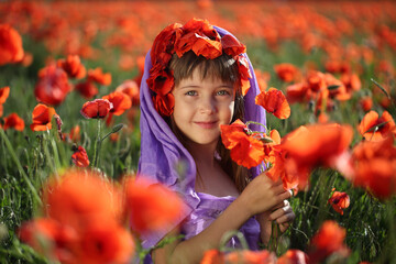 Little girl walks in a beautiful field of poppies