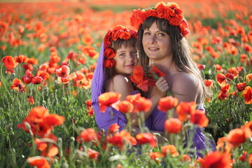 Mother and daughter are walking in a beautiful field of poppies