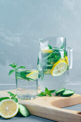 Health care, fitness, healthy food concept. Fresh cool mint lemon cucumber pour water, cocktail, detox drink, lemonade in a glass jug.
