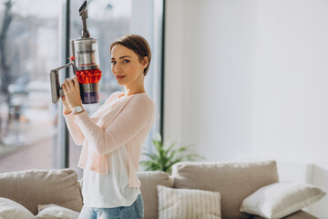 Young woman with rechargeable vacuum cleaner cleaning at home