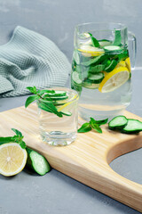 Health care, fitness, healthy food concept. Fresh cool mint lemon cucumber pour water, cocktail, detox drink, lemonade in a glass jug.
