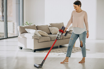 Young woman with rechargeable vacuum cleaner cleaning at home