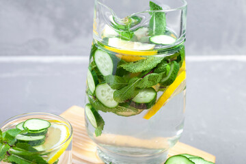 Health care, fitness, healthy food concept. Fresh cool mint lemon cucumber pour water, cocktail, detox drink, lemonade in a glass jug.
