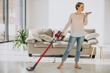 Young woman with rechargeable vacuum cleaner cleaning at home © Petro