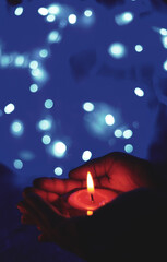 Burning candle in the hands of a girl with bokeh light. Christmas candles. Candlelight glowing in...