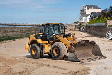 A construction excavator prepares a beach in Brittany for the arrival of tourists
