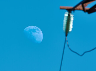 Fototapeta na wymiar day moon behind the support of the electroline