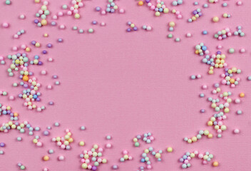 Small colorful pastel balls in a frame on pink paper