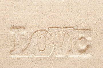 Word LOVE imprinted on sand