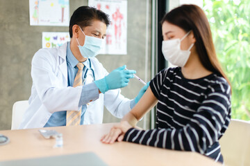 Senior doctor syringe injection vaccine to the young patient put on a mask in the hospital.Medical healthcare concept.