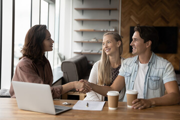Professional skilled female financial advisor or real estate agent shaking hands with satisfied...