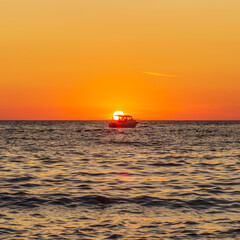 Fishing boat in the middle of the sea at sunset