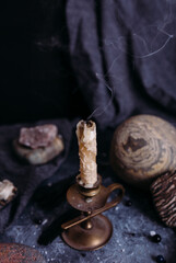 Extinguished candle, jug and stones on the witch table.
