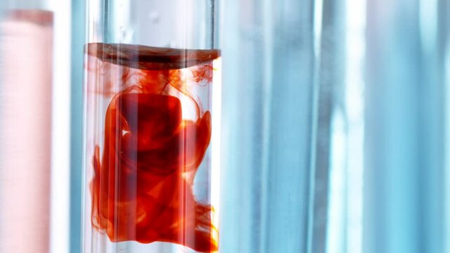 Super slow motion of drawing blood into syringe. Macro shot medical procedure syringe pulling red liquid into saline solution.