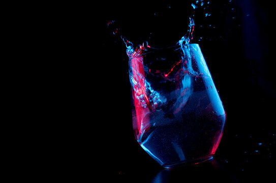Water highlighted in blue and red splashing into a glass