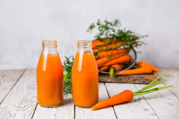 Carrot juice in glass bottles on a light table. Background image, central composition.