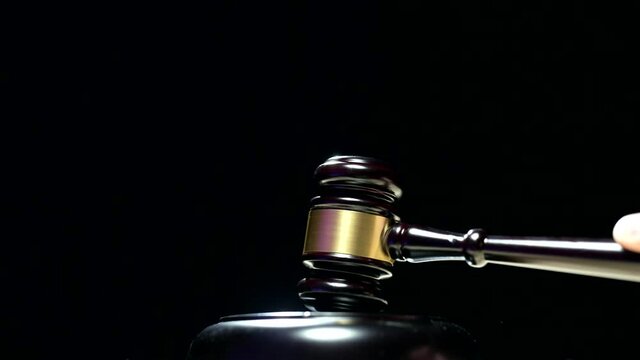 A judge is hitting gavel off a block in courtroom. Gavel is being struck to decide an auction or guilty verdict in court