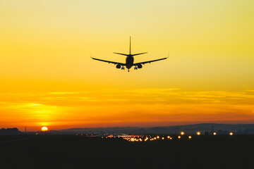 Fototapeta na wymiar Airplane landing on the runway during sunset and dusk