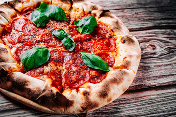 Pepperoni Pizza with Mozzarella cheese, salami, Tomato sauce, pepper, Spices and Fresh basil. Italian pizza on wooden table background