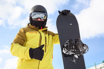 Snowboard and snowboarder with thumb up. Man wearing helmet, goggles and gloves. Extreme winter...
