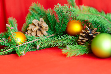 Obraz na płótnie Canvas Christmas background, green pine branches with cones and Christmas balls on a red background. Creative composition with border and copy space, top view. New year, holiday, christmas