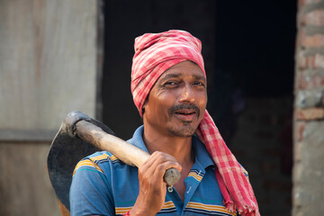 Smiling Indian Farmer holding a spade on her shoulder