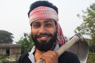 Smiling Indian Rural Farmer holding a Shovel in agricultural field