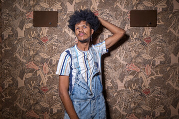 Afro-descendant man doing poses in studio with antique wallpaper background.