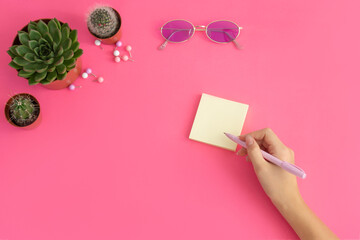 workspace  pink   , woman  hand  write  yellow sticker  .Girl  bloger  concept .