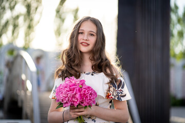 cheerful girl in a light summer dress against the background of a city park